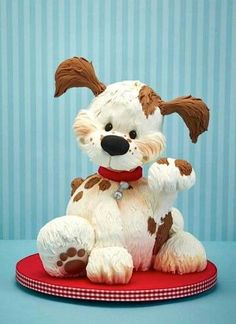 a small white and brown dog sitting on top of a red cushion next to a blue wall