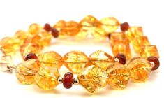 This 18" strand of faceted citrine nugget beads is the perfect way to bring a little sunshine into your life! With bright golden amber body color and rich orange patterning inside the crystals that resembles flowing honeycomb, this necklace is both beautiful and fun! Each citrine bead has a "swirled diamond" shape and slender rectangular facets that allow the light to reflect from all directions. Pomegranate red garnet rondels add pops of color, while the 14k yellow gold spacers and "S" clasp pi Faceted Amber Round Bead Jewelry, Amber Rondelle Gemstone Beads Jewelry, Amber Gemstone Beads Rondelle Jewelry, Formal Amber Jewelry With Gemstone Beads, Spiritual Orange Jewelry With Faceted Beads, Amber Jewelry With Faceted Beads For Gift, Gold Carnelian Jewelry With Faceted Beads, Elegant Amber Beaded Bracelet With Gemstones, Elegant Orange Bracelets With Faceted Beads