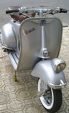 a silver scooter is parked on the sidewalk