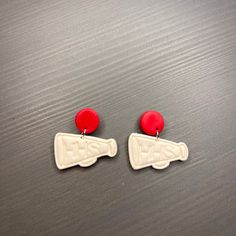 two red and white earrings sitting on top of a table