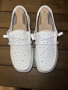 a pair of white shoes sitting on top of a wooden floor