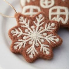 two brown and white snowflake ornaments sitting on top of a white plate next to each other