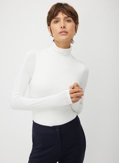 An elevated and comfortable turtleneck thong bodysuit with a high-performance update. Featuring a shaped sleeve and shoulder darts for a streamlined fit, plus built-in stretch that won’t slow you down. Use this breathable base layer to effortlessly build outfits or wear it solo with trousers for a clean, sophisticated office look. With the Ascend Turtleneck Bodysuit, getting dressed is a breeze—what you do with the rest of your day is up to you. Solid Fitted High Neck Turtleneck, Elegant High Stretch Tops With Thumbholes, Fitted Classic Long Sleeve Bodysuit, Fitted Solid Color Versatile Turtleneck, Versatile Fitted Turtleneck, Solid Fitted Versatile Turtleneck, Versatile Solid Fitted Turtleneck, Classic Stretch Bodysuit For Work, Chic Fitted Turtleneck With Thumbholes