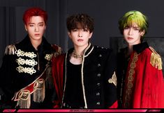 three young men with colorful hair standing next to each other in black and red outfits