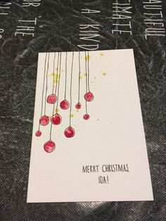 a christmas card with red balls hanging from it