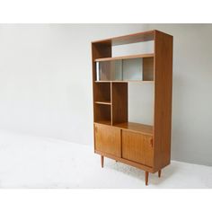 a wooden bookcase with glass doors and shelves on the front, against a white wall