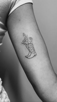 a woman's arm with a tattoo on it that has flowers in a vase