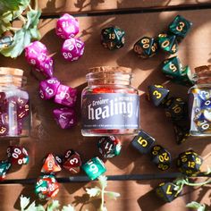 various colored dices and jars with writing on them sitting on a table next to plants