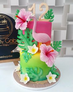 there is a cake decorated with flowers and a flamingo on the top, next to a box