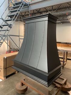 a large black stove top sitting in the middle of a room next to some stairs