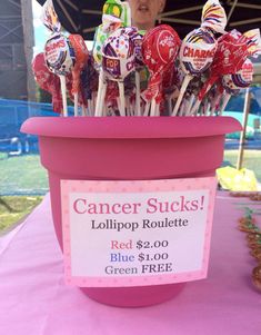 a pink bucket filled with candy sticks on top of a purple tablecloth covered field