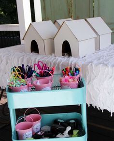 there are many craft supplies on the table with little houses in the backgroud