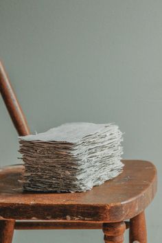 stack of papers sitting on top of a wooden chair