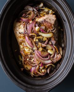 the meat is covered with onions and spices in the crock pot, ready to be cooked