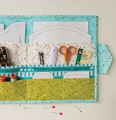 scissors and sewing supplies are in the pocket of a crafting kit holder that is made out of scrapbook pages