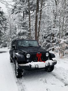 a jeep is parked in the snow with a red bow on it's hood