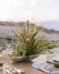 the table is set with silverware and flowers in a bowl on top of it