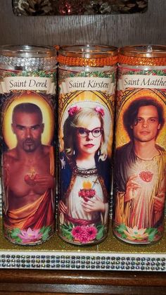 three candles with pictures of saints on them are sitting on a shelf in a store