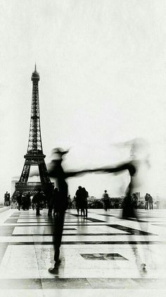 black and white photograph of people dancing in front of the eiffel tower