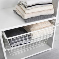 a white shelf filled with folded towels and blankets