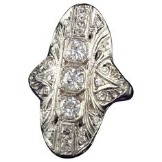 Beautiful Antique Art Deco 14K White Gold Old Cut Diamond Filigree Shield Ring. This gorgeous antique cocktail ring is crafted in 14k white gold. The ring holds beautiful white diamonds on top of the ring and sits low on the finger. The ring is in good condition. Item #R1776 Metal: 14K White Gold Weight: 4.9 Grams Size: 6 Diamonds: Approximately .75 cts Color: H Clarity: VS2 - SI1 Measurements: Top of the ring measures 27.2 mm wide and band measures 1.93 mm wide. Measurements off the finger: 5 m Art Deco Ring In Diamond White With Jewels, Victorian Platinum Diamond Ring With Hallmark, Victorian Platinum Diamond Ring Hallmarked, Antique 14k White Gold Diamond Ring Hallmarked, Antique 14k White Gold Jewelry With Diamond Accents, Vintage Platinum Jewelry With Diamond Accents, Vintage Silver Platinum Jewelry, Vintage Events Silver Platinum Jewelry, Art Deco Silver Diamond Ring In 14k Gold