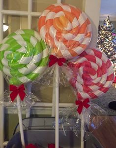 three lollipops are sitting on top of each other in front of a christmas tree