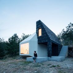 a person standing in front of a small house with stairs leading up to the roof