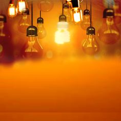 many light bulbs hanging from the ceiling in an orange and yellow room with blurry lights