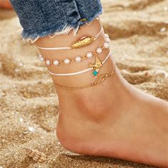 Add a little oomph to your latest pedicure or favorite shoes when you accessorize with this gleaming 18-karat gold-plated anklet set. Wear them stacked together or solo for a boho-chic look. Includes white peanut charm anklet, white and turquoise bird charm anklet, pearl station anklet and open abstract anklet (four pieces total) 2.59" diameter Lobster claw clasp 18k gold-plated copper / turquoise / pearl / vibre Peanuts Charm, Tassel Anklet, Foot Chain, Charm Anklet, Chain For Women, Rice Bead, Bird Charm, Braided Rope, Beaded Pendant