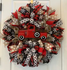 a christmas wreath with a red truck and polka dot ribbon on the front door to give as a decoration