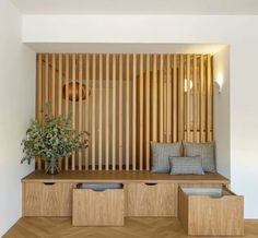 a wooden bench sitting next to a plant on top of a hard wood floor