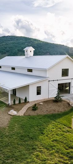 a large white barn sitting on top of a lush green hillside