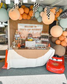 a birthday party with balloons and desserts on the table, including an orange car