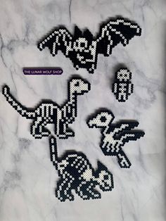 four pixellated images of dinosaurs on a white marble surface with the word dino spelled in black letters