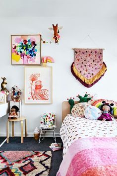 a bedroom decorated in pink, yellow and white with pictures on the wall above the bed