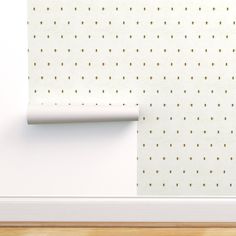 a white wall with gold dots on it and a roll of paper in the corner