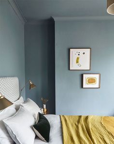 a bedroom with blue walls and white bedding, yellow blanket on the headboard