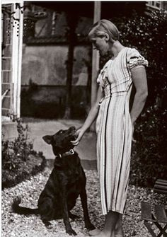 an old photo of a woman holding the hand of a dog in front of her