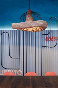 a wooden table sitting under a hanging light over it's head in front of a metal wall