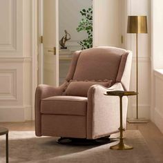 a living room with a chair, table and lamp on the floor in front of a door