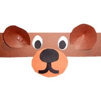 a brown paper dog head hanging on a wall with eyes and nose cut out from it's side