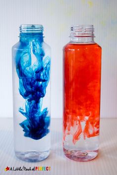 two glass jars filled with blue and red liquid sitting on top of a white table