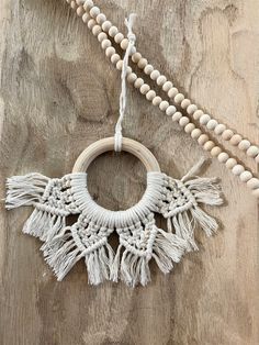 a wooden beaded necklace with tassels hanging from it's side on a wood surface