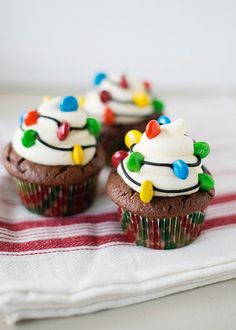 christmas light cupcakes with white frosting and colorful candies are on a striped napkin