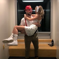 a man holding a woman in his arms while they both wear white socks and red caps