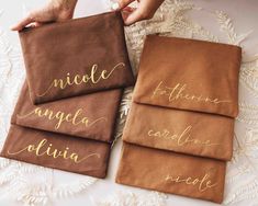 three brown towels with gold lettering are on a white lace doily, one is folded and the other has an embroidered name