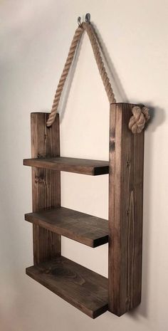 a wooden shelf with rope hanging from it's sides and two shelves on each side