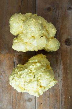 two pieces of cauliflower sitting on top of a wooden table next to each other