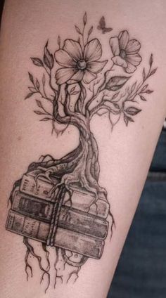 a tree with flowers growing out of it's trunk and some books on the ground