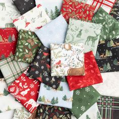 many different types of christmas fabric are arranged in rows on a tablecloth with trees, deers and snowflakes